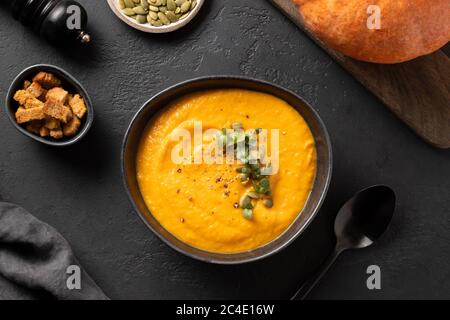 Kürbissuppe auf schwarz garnieren. Draufsicht. Stockfoto