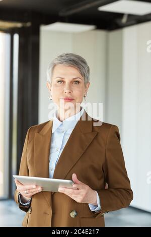 Porträt einer reifen Geschäftsfrau in formeller Kleidung Blick auf Kamera, während mit digitalen Tablet im Büro Stockfoto
