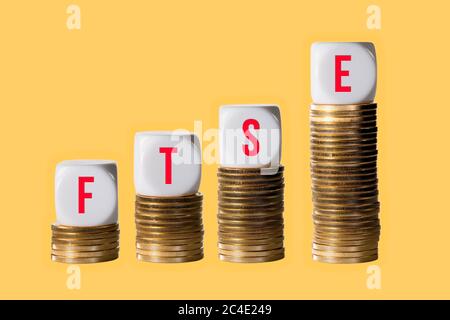 Steigender Wert im Investitionsplan in Aktien und Aktien mit FTSE auf Blöcken auf Stapel von Goldmünzen. Zeigt einen Anstieg des Index in London Stockfoto