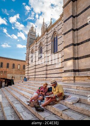 Ein reifes Paar, das auf der Südfront der Kathedrale von Siena skizziert. Siena. Italien. Stockfoto