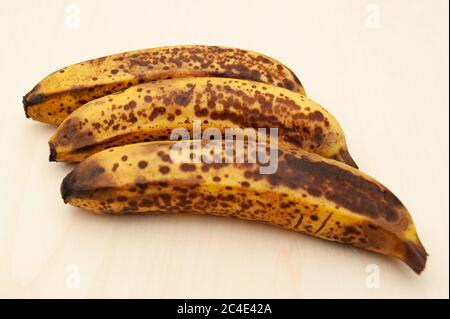 Drei reife Bananen isoliert auf hellem Holzhintergrund. Draufsicht. Speicherplatz kopieren. Stockfoto