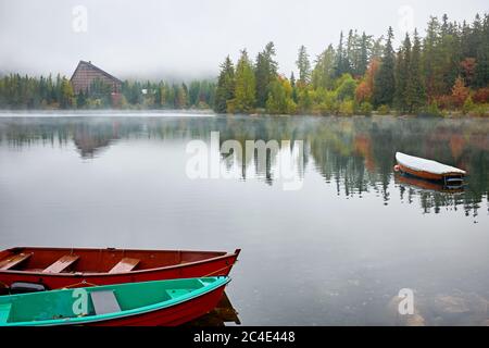 Nebliger Herbst Strbske See mit Rückbau und Boote auf dem Wasser in der Hohen Tatra Nationalpark, Slowakei Stockfoto