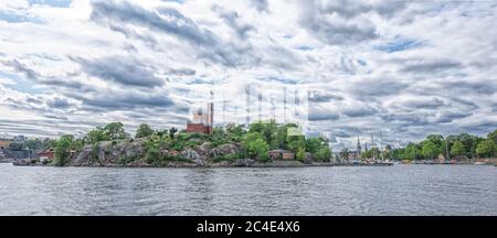 STOCKHOLM SCHWEDEN - 2. AUGUST 2019: Panoramablick auf die Küste der Insel Skeppsholmen mit Schloss und Pier für Boote Stockfoto