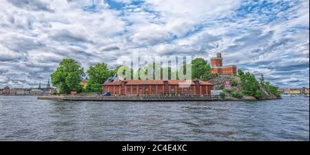 STOCKHOLM SCHWEDEN - 2. AUGUST 2019: Panoramablick auf die Küste der Insel Skeppsholmen mit Schloss und Pier für Boote Stockfoto