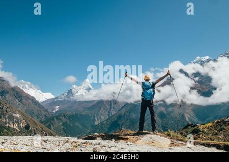Konzept für aktive Ferien. Junger Wanderer Backpacker Mann aufsteigende Arme mit Trekking-Stöcke genießen den Thamserku 6608m Berg in großer Höhe Stockfoto