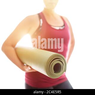 Junge Frau hält gerollte Gummi-Gymnastik-Yoga-Matte auf dem weißen Hintergrundlicht Start Morgen Yoga-Übungen. Gesunde und aktive Menschen lifestyl Stockfoto