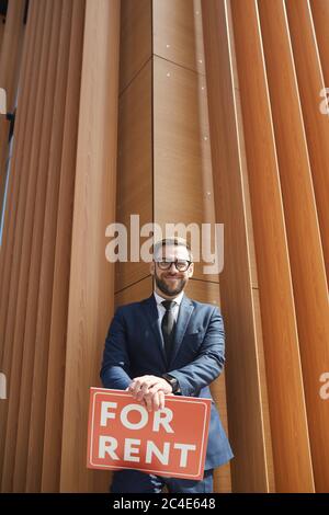 Porträt von makler in Anzug halten Plakat lächelnd auf Kamera, während im Freien stehen Stockfoto