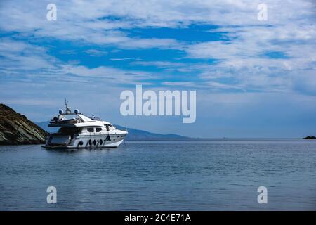 Kea, Otzias, Griechenland. Luxus-weiße Farbe Yacht in der Nähe des Landes der Insel Tzia in der Mitte des blauen ruhigen Meer verankert. Spiegelung des Schiffes, bewölkt Stockfoto