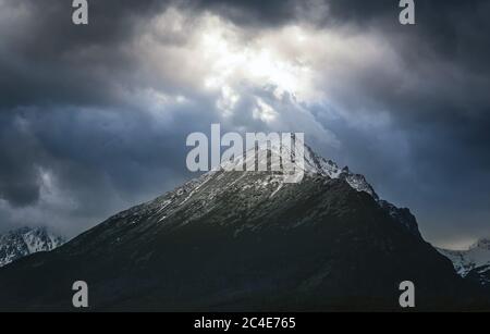 Dramatischer Himmel mit Sonnenstrahlen, die durch schwere Wolken über dem Slavkowski-Gipfel brechen siit ist der vierthöchste Berg im Berg hohe Tatra Stockfoto