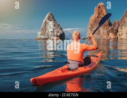 Kajak. Sportler Kajakmann genießt Abenteuer auf ruhigen Meer mit blauem Wasser. Freizeitaktivitäten auf dem ruhigen blauen Wasser. Das Konzept eines aktiven und Stockfoto