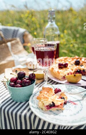 Tisch im Garten serviert mit schönen Weingläser, Teller, Silberbesteck und Geschirr, Tischdecke, süße Kirschkuchen und frische Kirschen Stil Stockfoto