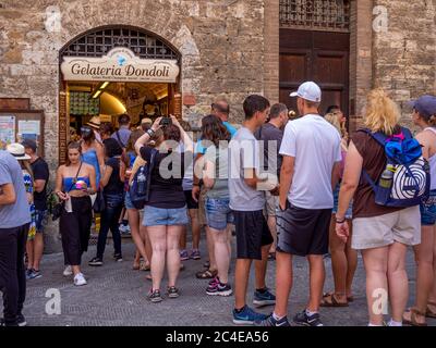 Touristen stehen vor einer preisgekrönten Gelateria Schlange. San Gimignano, Italien. Stockfoto