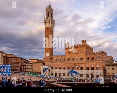 Prozession der Onda Contrada, die am Palazzo Pubblico auf der Piazza del Campo vorbeimarschiert. Siena. Italien. Stockfoto