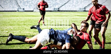 Digitale Composite-Bild von Team von Rugby-Spieler, die sich gegenseitig, um den Ball im Stadion zu gewinnen Stockfoto