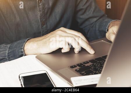 Hand Mann drücken auf Trackpad auf Laptop und mit Smartphone mit Online-Shopping. Stockfoto