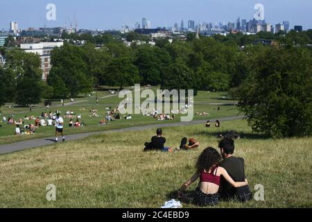 Die Menschen entspannen sich auf Primrose Hill, London, während Gewitter und sintflutartige Regenfälle über Großbritannien hereinfegen werden, was eine Woche mit prallen Sonnenstrahlen und sengenden Temperaturen ausklingen lässt. Stockfoto