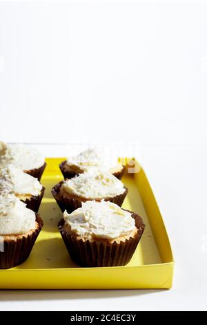 Vegane Vanille Cupcake mit Kokoscreme Zuckerguss in Papierbecher auf weißem Hintergrund.Vertikale Ausrichtung, Kopierraum Stockfoto