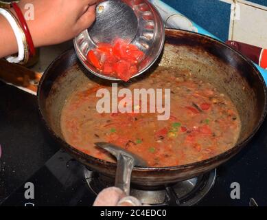 Eine indische Frau oder Hausfrau setzen Zutaten beim Kochen oder die Zubereitung von traditionellen indischen Gericht oder Lebensmittel Dal Tadka (Linsen) Stockfoto