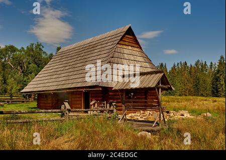 Holzhütte in den Bergen zwischen Wiesen an einem sonnigen Sommertag Stockfoto