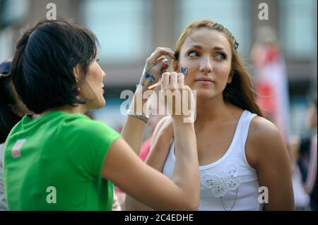 Frau Street Artist macht Gesichtsmalerei für ein kleines Mädchen mit Pinsel. Juni 2013. Kiew, Ukraine Stockfoto