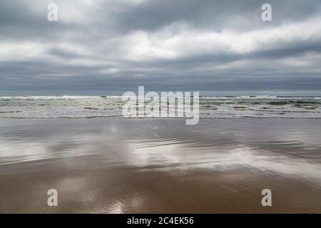 Wolkenspiegelungen im Sand, am Cannon Beach an der Küste von Oregon Stockfoto