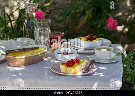 Frühstück im Garten mit Aufläufen, Beeren, Saucen und Getränken. Rustikaler Stil. Stockfoto