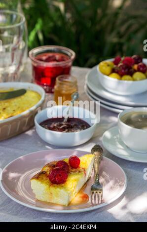 Frühstück im Garten mit Aufläufen, Beeren, Saucen und Getränken. Rustikaler Stil. Stockfoto