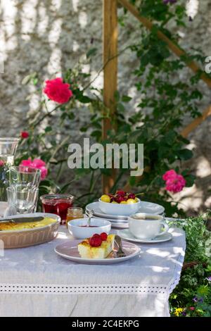 Frühstück im Garten mit Aufläufen, Beeren, Saucen und Getränken. Rustikaler Stil. Stockfoto