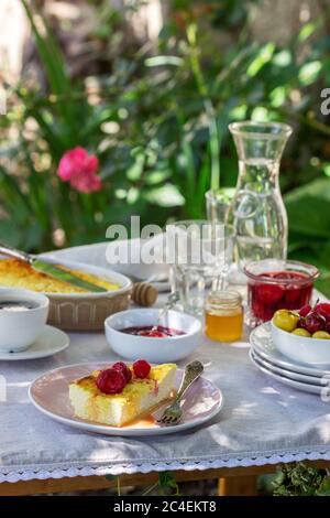 Frühstück im Garten mit Aufläufen, Beeren, Saucen und Getränken. Rustikaler Stil. Stockfoto