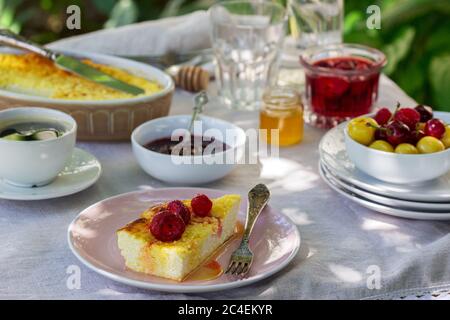 Frühstück im Garten mit Aufläufen, Beeren, Saucen und Getränken. Rustikaler Stil. Stockfoto