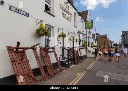 Leigh-on-Sea, Großbritannien. Juni 2020. Straßenszene im Sommer vor dem Crooked Billet Pub in der Leigh-on-Sea High Street, Essex. Gestapelte Tische, hängende Körbe und Fußgänger in warmer Kleidung sorgen für eine lebhafte Küstenatmosphäre. Das krumme Billet mit Tischen an der Wand. Leute in Old Leigh, Essex, genießen das warme Wetter und weniger überfüllte Strände. Penelope Barritt/Alamy Live News Stockfoto