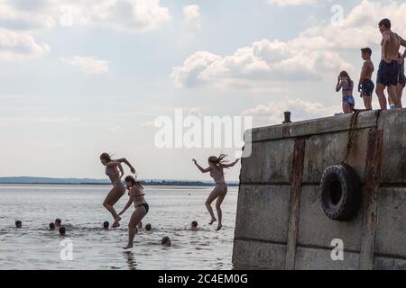 Leigh-on-Sea, Großbritannien. Juni 2020. Eine Gruppe von Menschen genießt einen warmen Tag am Bell Wharf Beach in Leigh-on-Sea, Essex, und springt vom Betonpier in das ruhige Wasser der Themse Mündung. Die Szene fängt spontanen Sommerspaß und das Engagement der Gemeinschaft an einem beliebten britischen Küstenort ein. Leute in Old Leigh, Essex, genießen das warme Wetter und weniger überfüllte Strände. Penelope Barritt/Alamy Live News Stockfoto