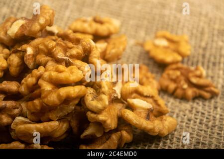 Geschälte Walnüsse in loser Schüttung auf einem Holztisch mit grober Struktur und Quaste. Gesunde Ernährung. Fitness-Diät. Nahaufnahme Stockfoto