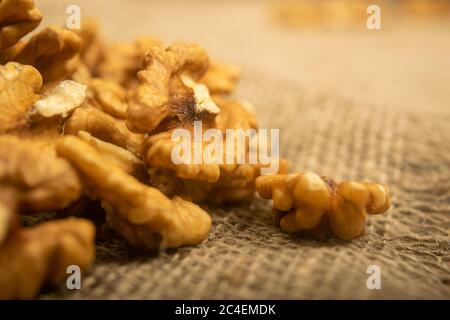 Geschälte Walnüsse in loser Schüttung auf einem Holztisch mit grober Struktur und Quaste. Gesunde Ernährung. Fitness-Diät. Nahaufnahme Stockfoto