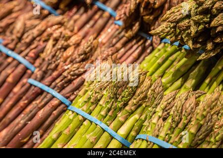Eine Nahaufnahme von grünem und purpurem Spargel zum Verkauf an einem Marktstand Stockfoto