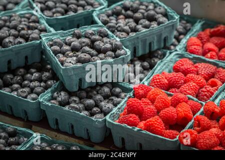 Punnets von Himbeeren und Heidelbeeren zum Verkauf auf einem Marktstand Stockfoto