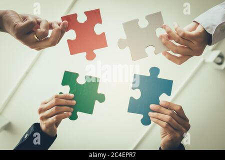 Multi-ethnische Gruppe von Business-Profi setzen vier Puzzle-Stücke zusammen. Stockfoto
