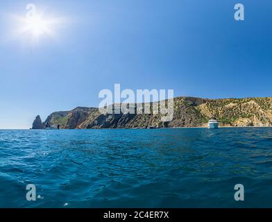 Yachten im Meer auf einem Hintergrund von felsigen Küsten. Meereslandschaft mit Yachten und felsiger Küste. Das Konzept der Reise, Entspannung, aktiv und gesund Stockfoto