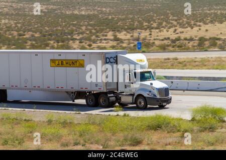 Apple Valley, CA / USA – 16. Mai 2020: White J.B. Jagen Sie auf der Interstate 15 in der Mojave-Wüste in der Nähe der Stadt Apple Valley, Kalifornien, einen Sattelschlepper. Stockfoto