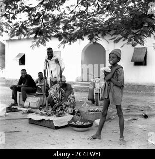 Männer und ein Junge, der Lebensmittel und Souvenirs in der Elfenbeinküste verkauft 1963 Elfenbeinküste 1960 Stockfoto