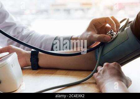 Arzt mit Stethoskop Tippen Sie im Büroraum auf den Arm des Patienten. Stockfoto
