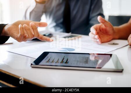 Geschäftsteam mit einem digitalen Tablet, während Sie Papierkram durcharbeiten. Stockfoto