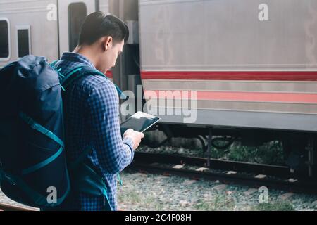 Smart junge asiatische Mann mit Tablet am Bahnhof. Stockfoto