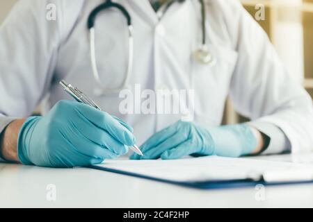 Der Arzt schreibt einen zusammenfassenden Bericht in seinem Labor auf den Tisch. Stockfoto