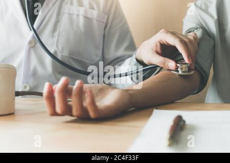 Nahaufnahme Arzt mit Stethoskop Tippen Sie im Büroraum auf den Arm des Patienten. Stockfoto