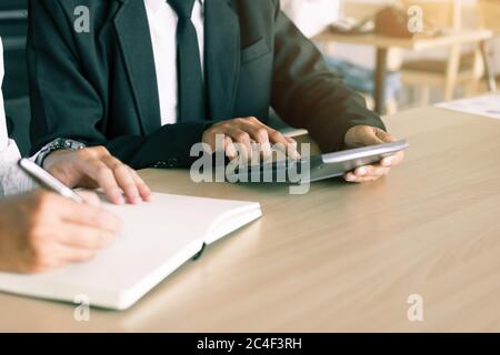 Verkäufer drücken Rechner und Kunden schreiben Notiz Bericht auf Notebook. Stockfoto