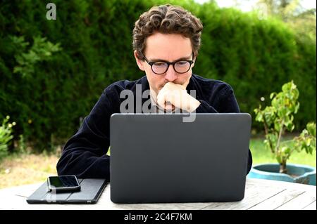 Junger Mann mit Brille, der während der Krise von 19 von zu Hause aus arbeitet Stockfoto
