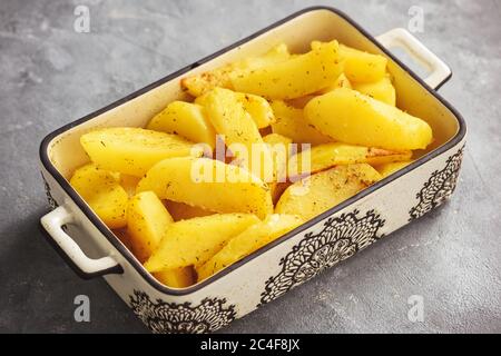 Backkartoffeln mit Knoblauch und Gewürzen auf Holzhintergrund. Stockfoto