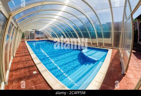 Überdachter Sommerpool. Der überdachte Bereich des Außenpools für das Hotel. Wasser hält die Wärme länger zurück und schützt vor Wind. Stockfoto