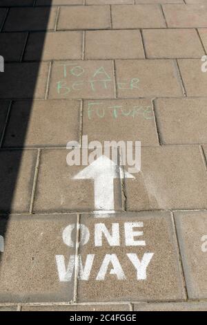 One Way Covid 19 soziale Distanzierungsbotschaft auf einem Bürgersteig in Bristol. Für eine bessere Zukunft in grün hinzugefügt. Clifton Village, Bristol, England, Großbritannien Stockfoto